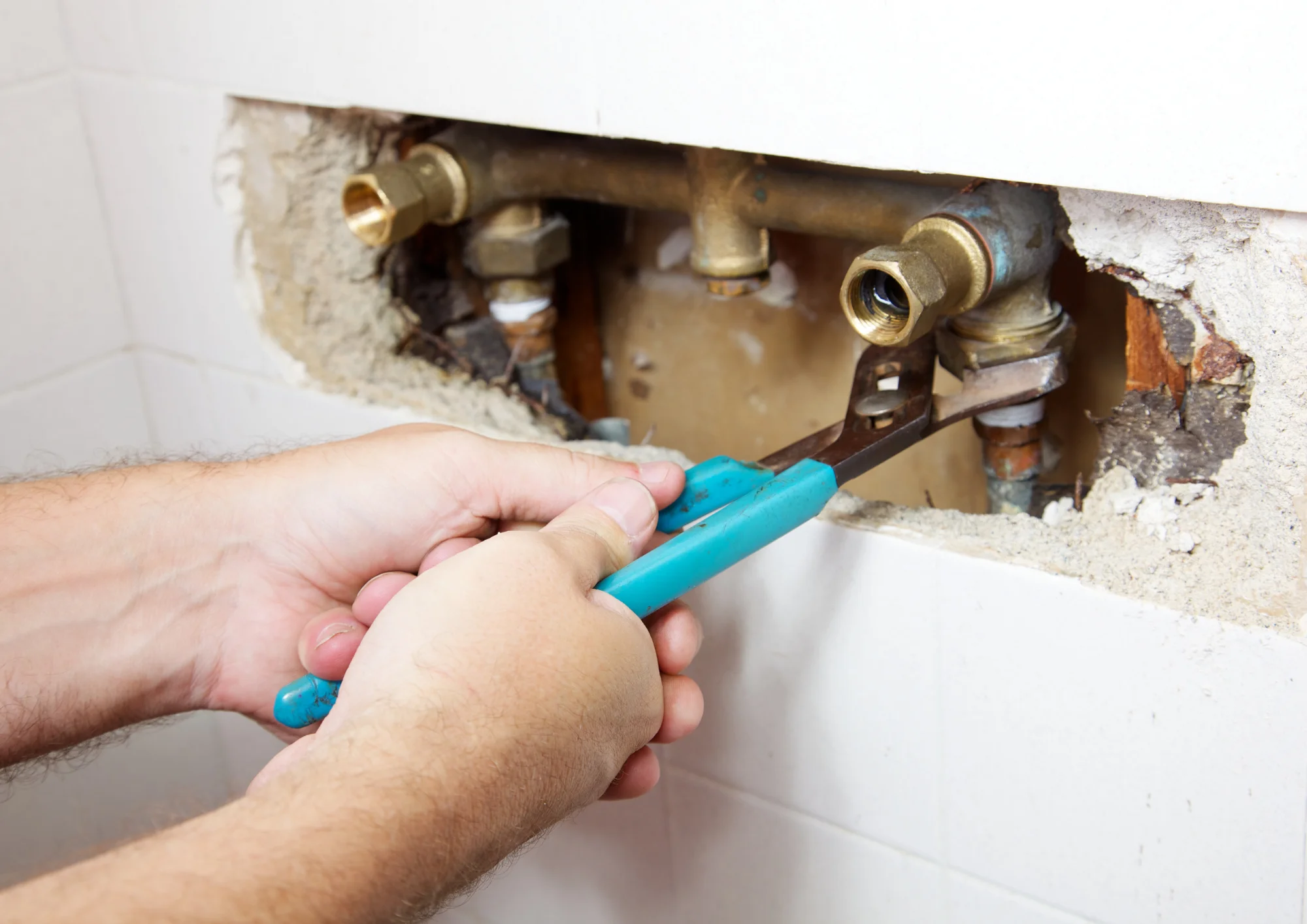 Homeowner and plumber reviewing a leaking wall pipe to determine insurance coverage
